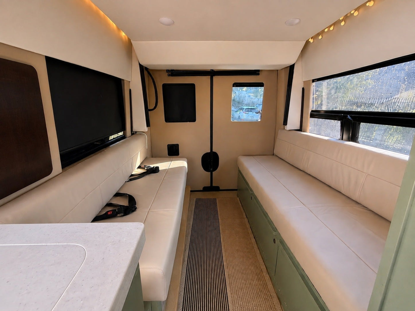 with a stunning beach and ocean view from the window.|Spacious RV rental interior featuring opposing cushioned benches — photo 3