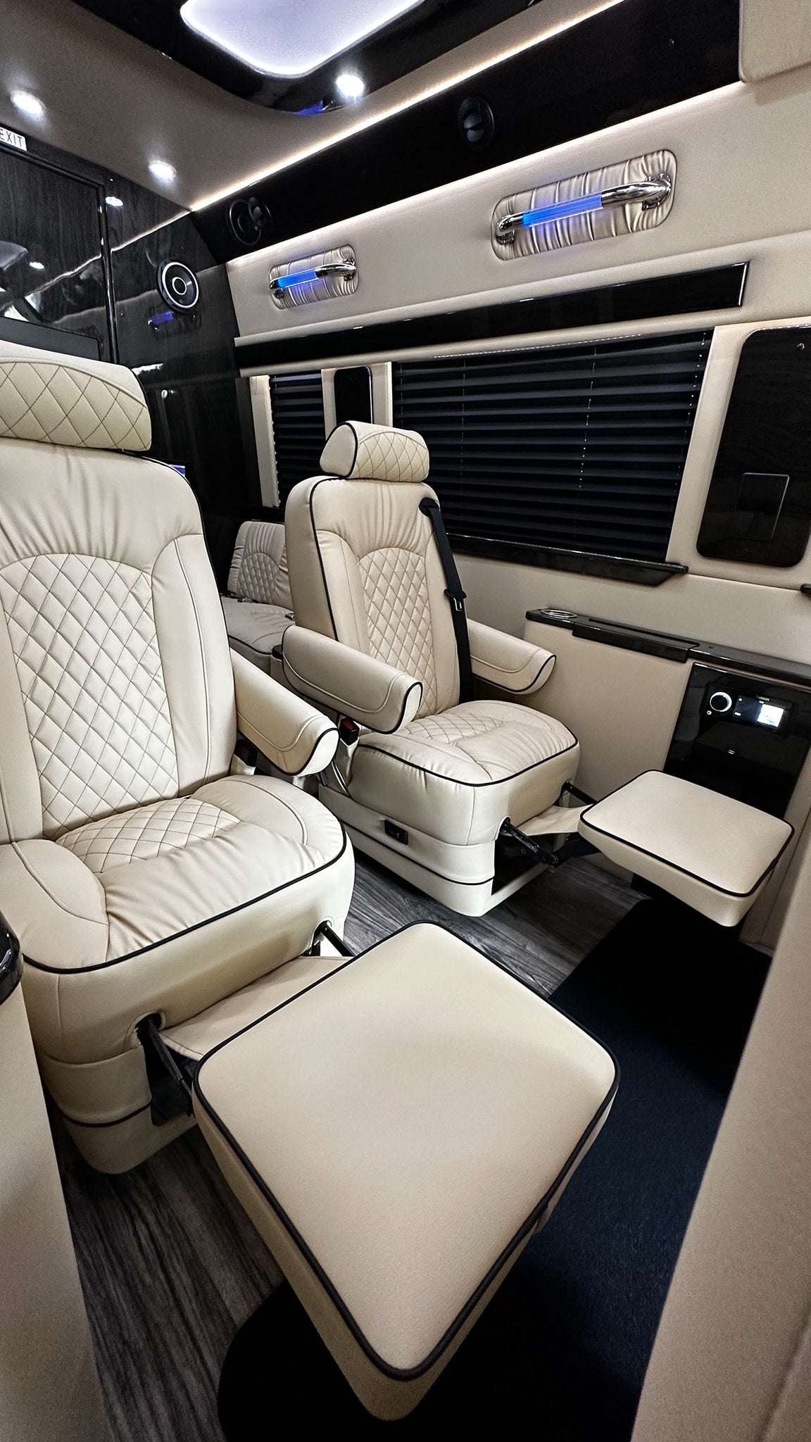 Luxurious RV rental interior with cream quilted captain's chairs, adjustable footrests, ambient lighting, and privacy blinds. — photo 15