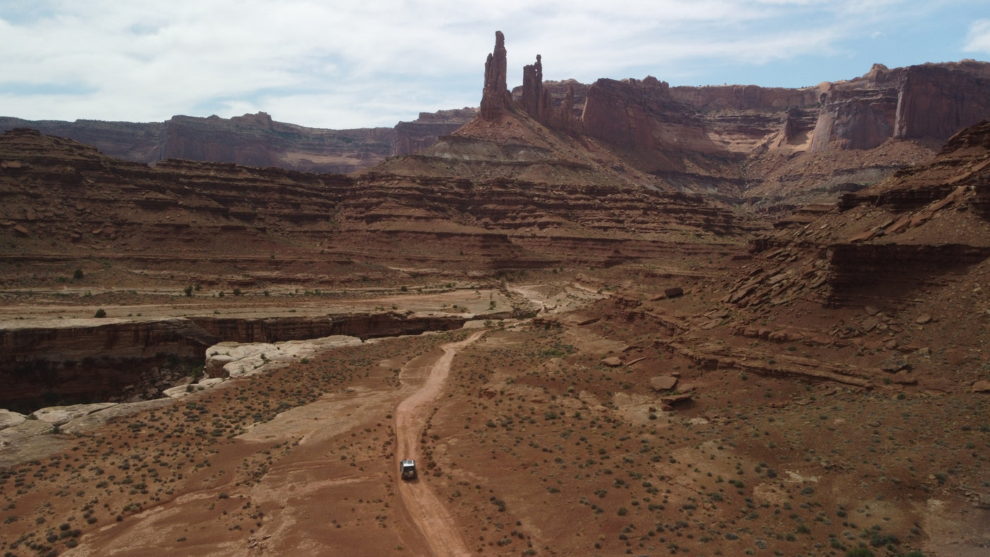 Experience adventure with an RV rental on a desert road, amidst towering red rock formations and a vast canyon landscape.