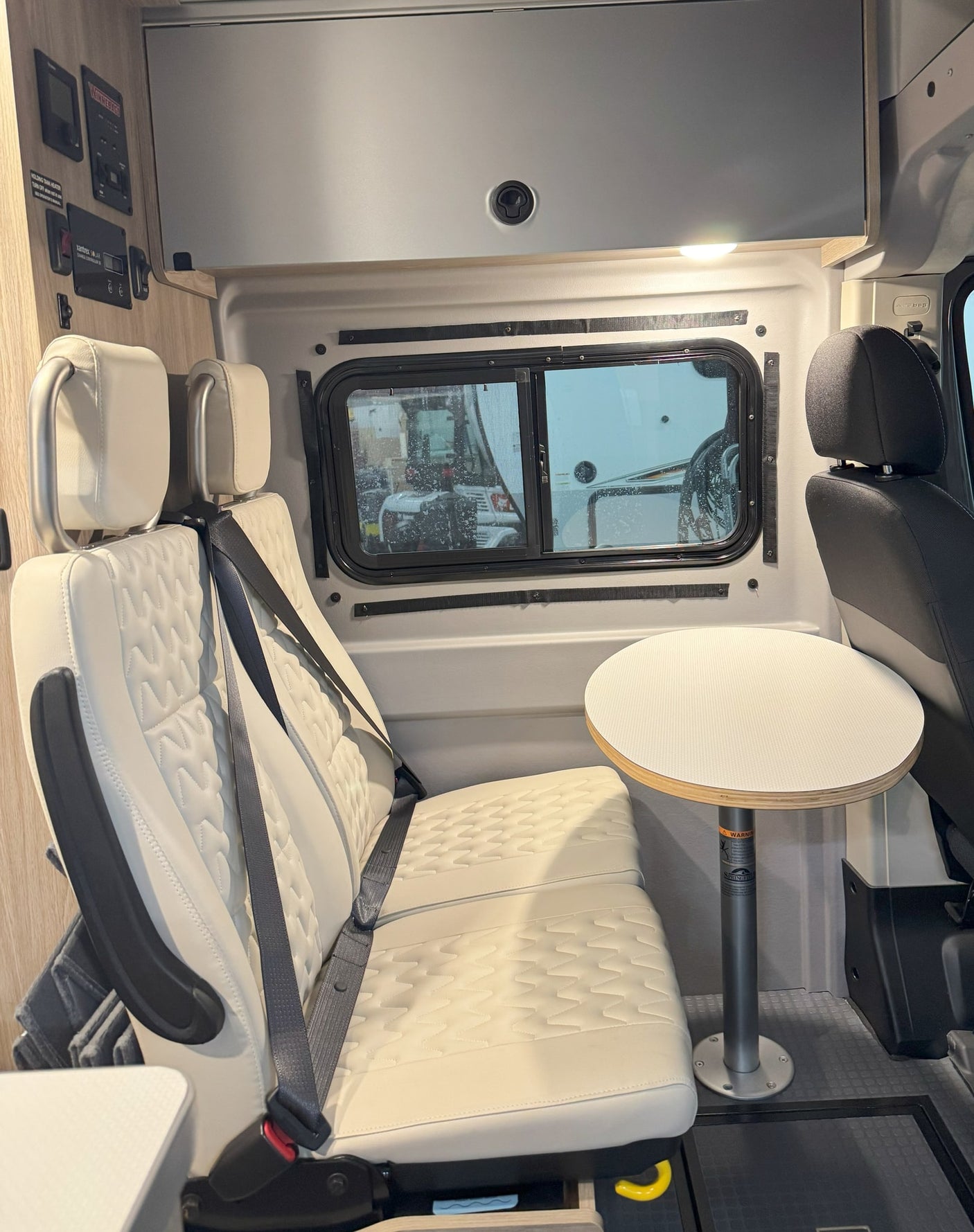 Explore this RV rental's cozy interior with quilted seating, a dining table, and Winnebago control panel.