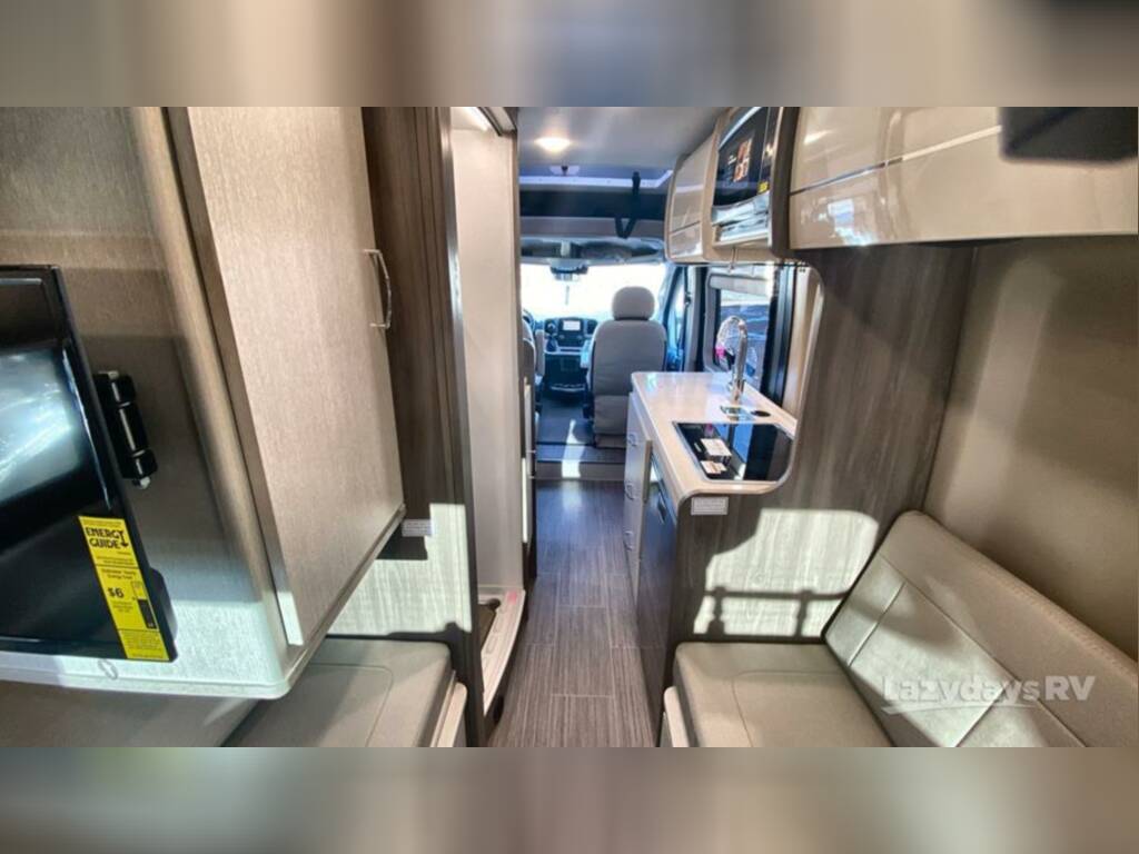 functional sleeping area with windows and storage in a camper van.|Elevated RV rental pop-top sleeping area with textured mattress. Ideal for comfortable camper adventures.|Spacious front cab interior of an RV rental — photo 15