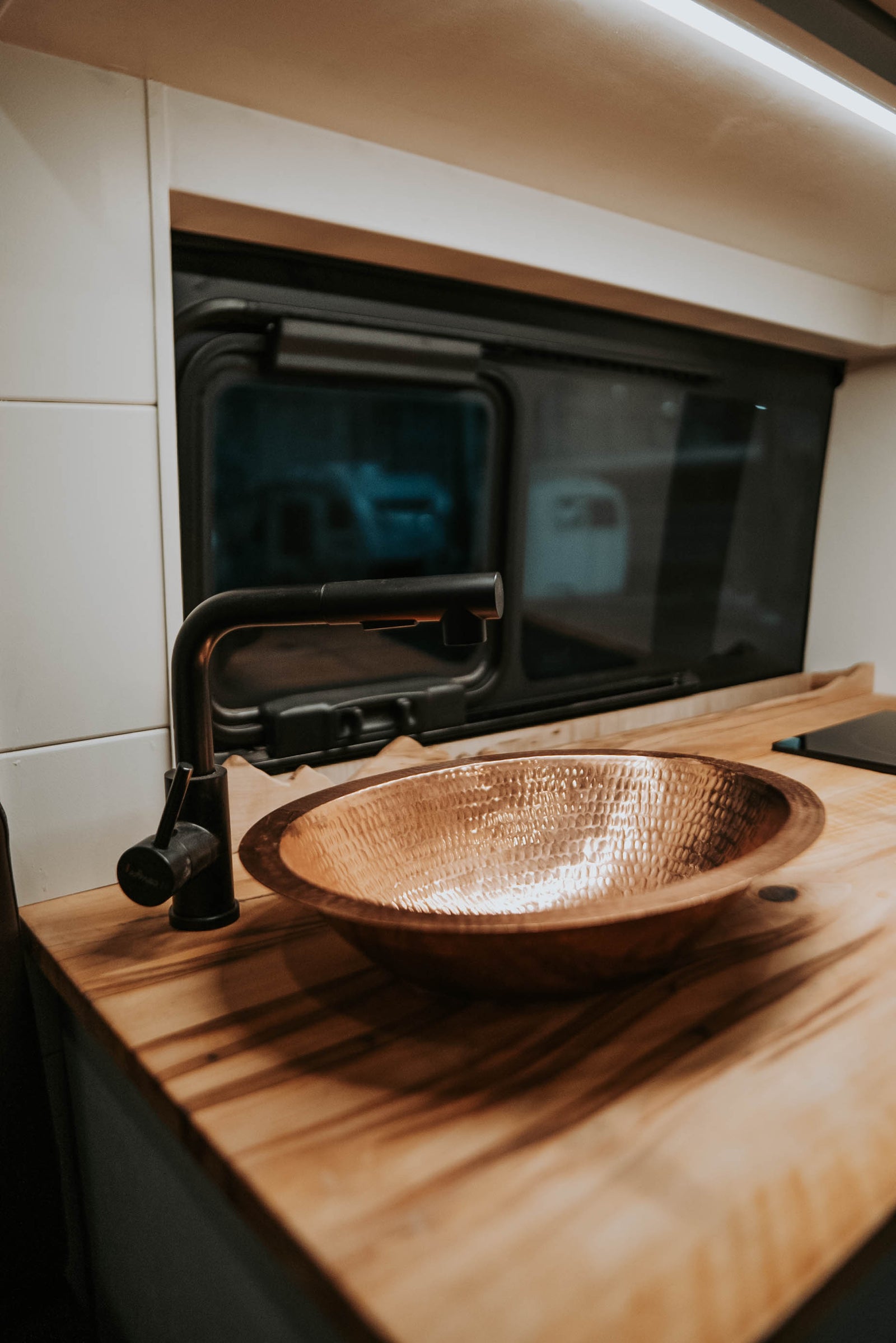 showing its wood interior and convenient pull-out storage.|RV rental's inviting kitchen: hammered copper sink