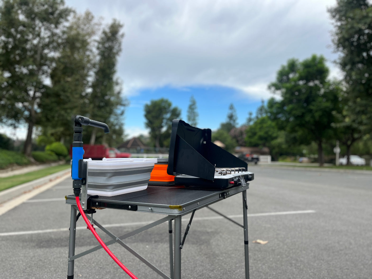 RV rental adventure prep: A portable camping kitchen, featuring a two-burner stove and pump sink, set on a folding table.