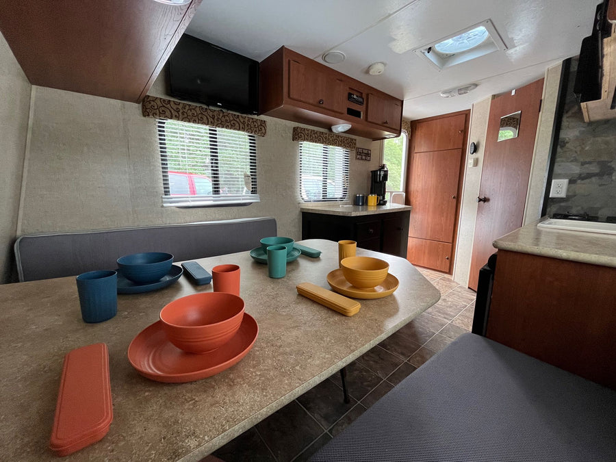 facing a colorful dinette on right. Ideal for travel.|Step into this RV rental: a compact interior features a dining table with colorful tableware