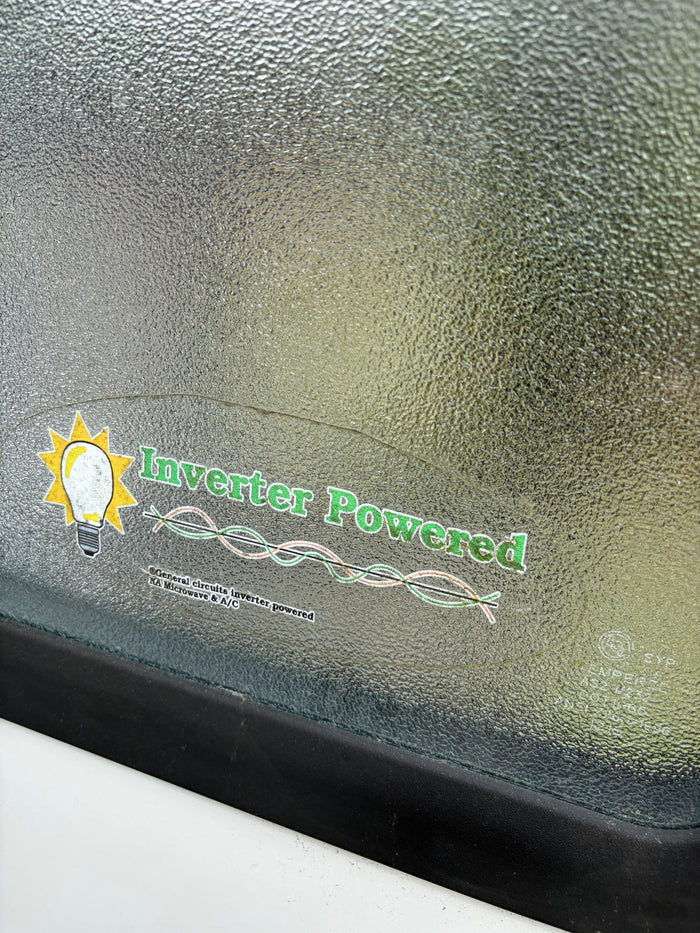 Sticker on an RV rental's textured window announces 'Inverter Powered' for general circuits, microwave, & A/C.