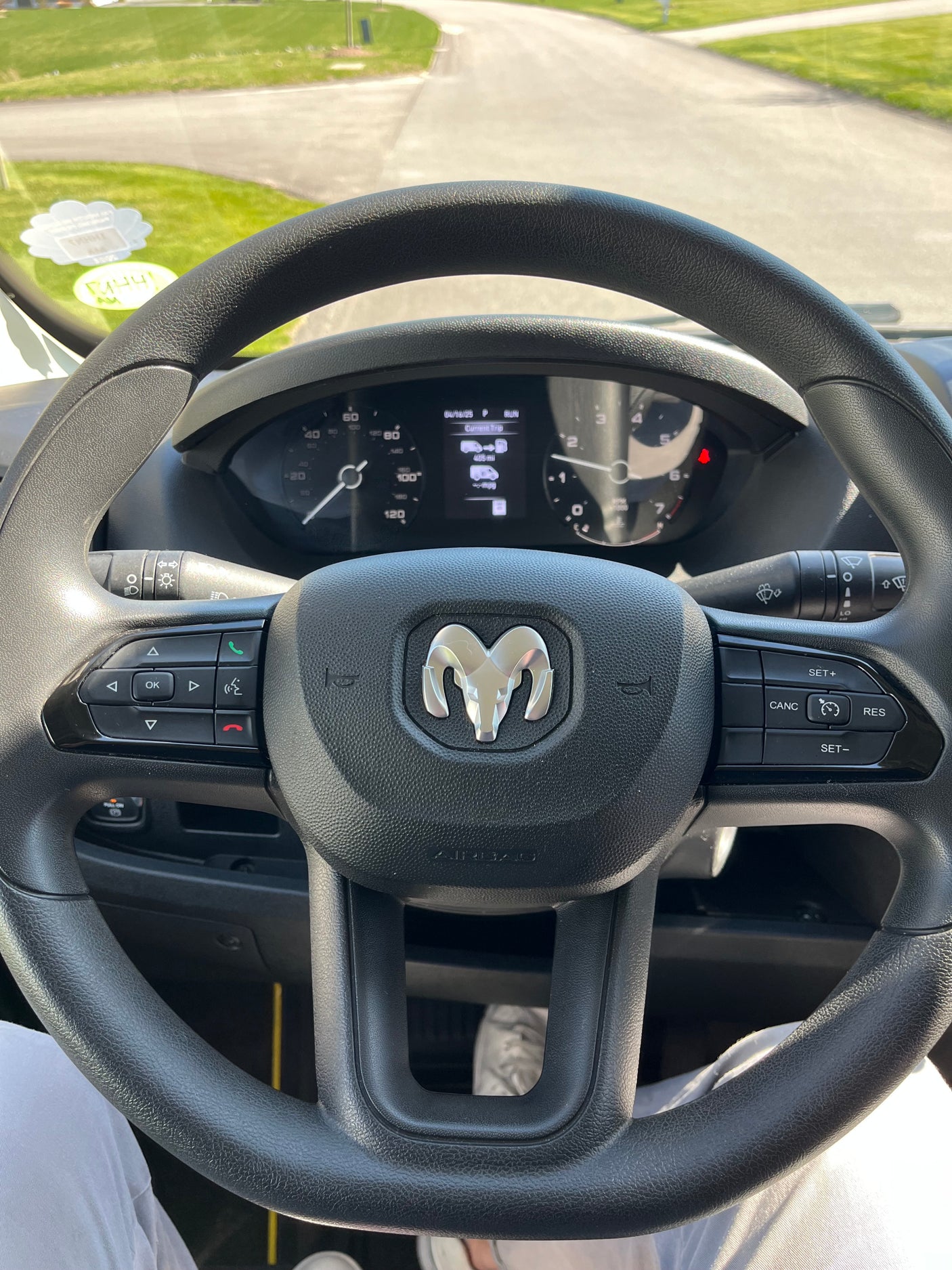 Driver's view inside an rv rental, showing the Ram steering wheel, dashboard with 405 mi trip, and the sunny road ahead.