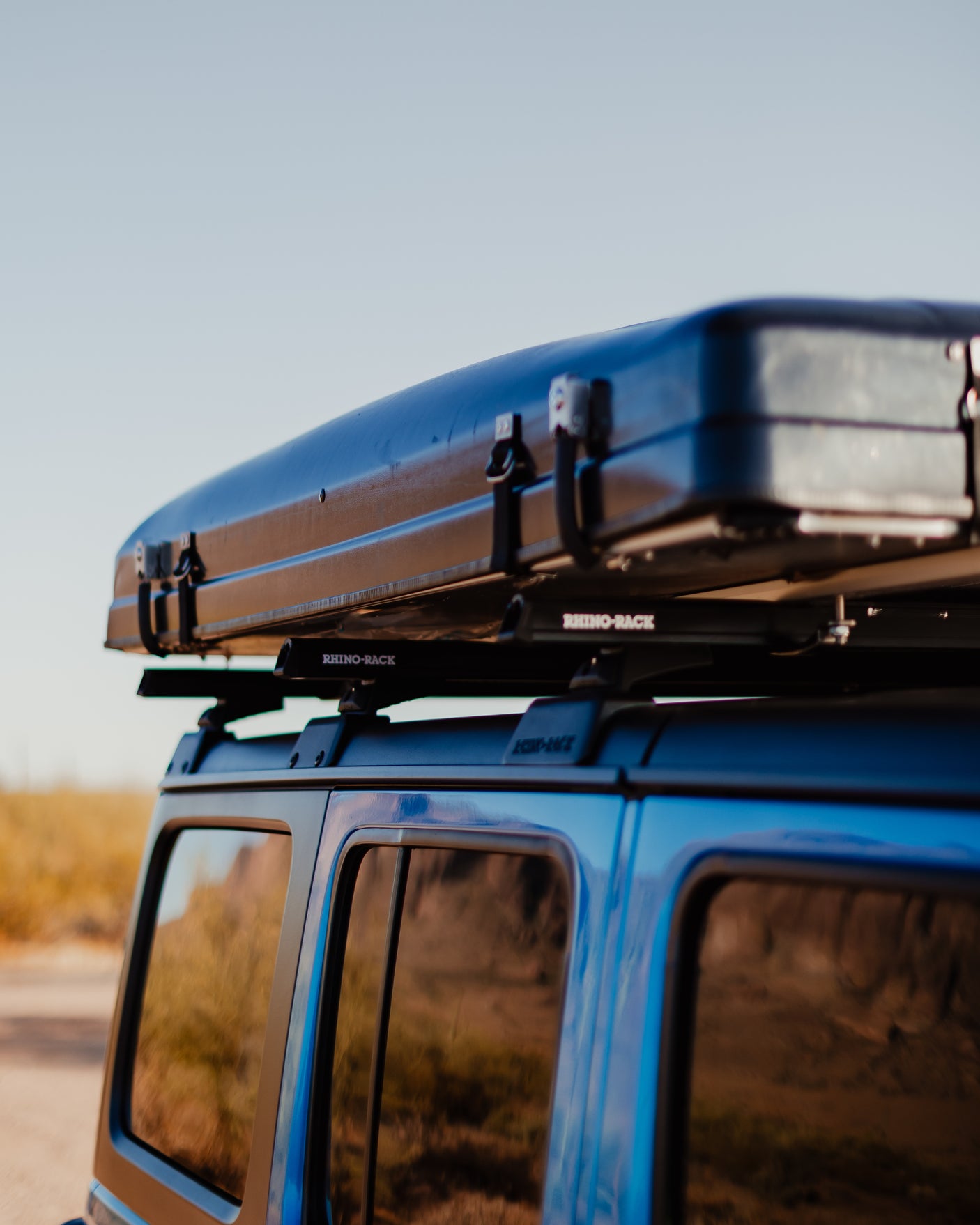 Blue vehicle with a black Rhino-Rack rooftop tent, ready for your RV rental adventure.