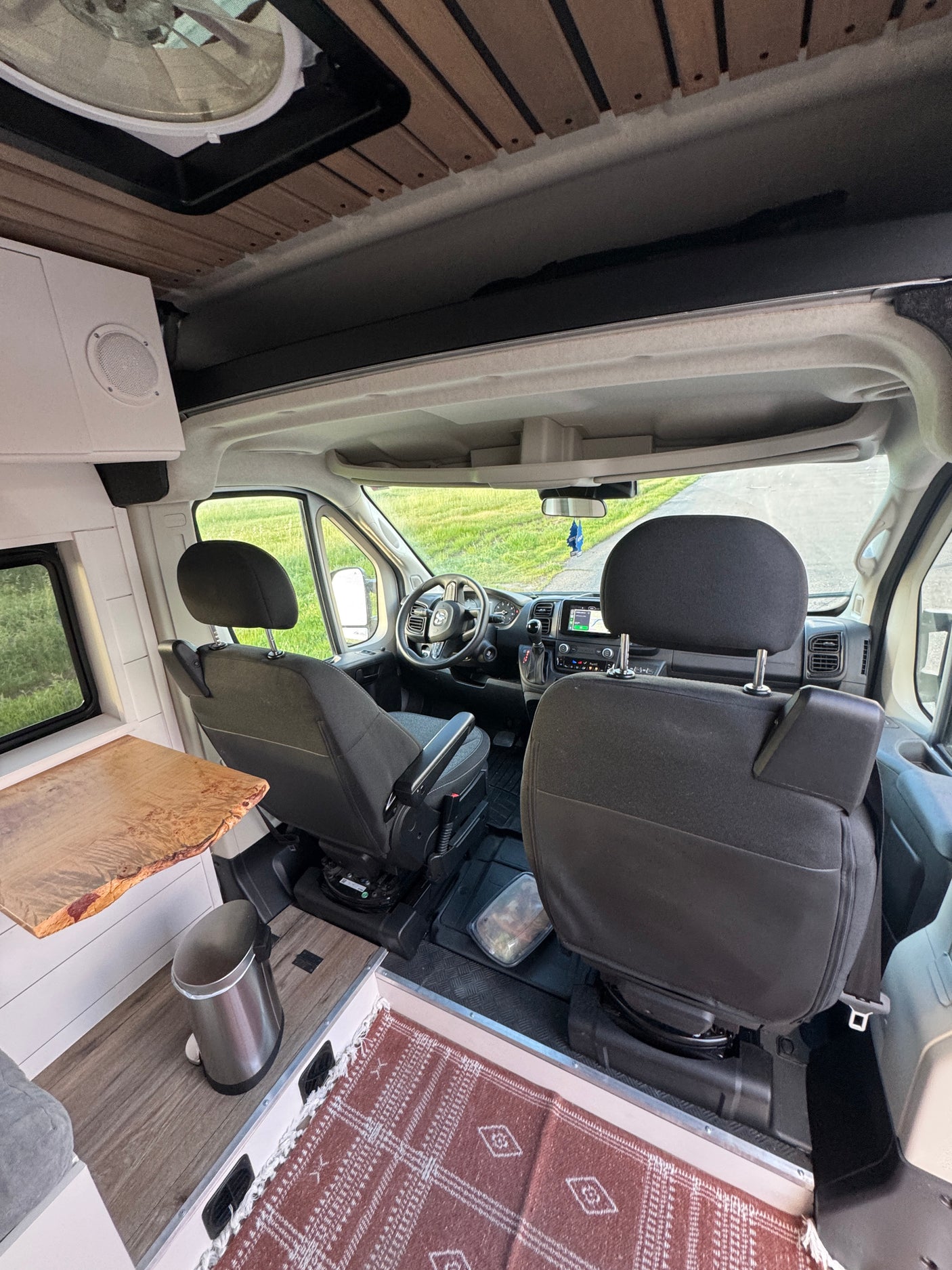 Inside this RV rental: a camper van conversion from the rear, showing front seats, dashboard, and wood accents.