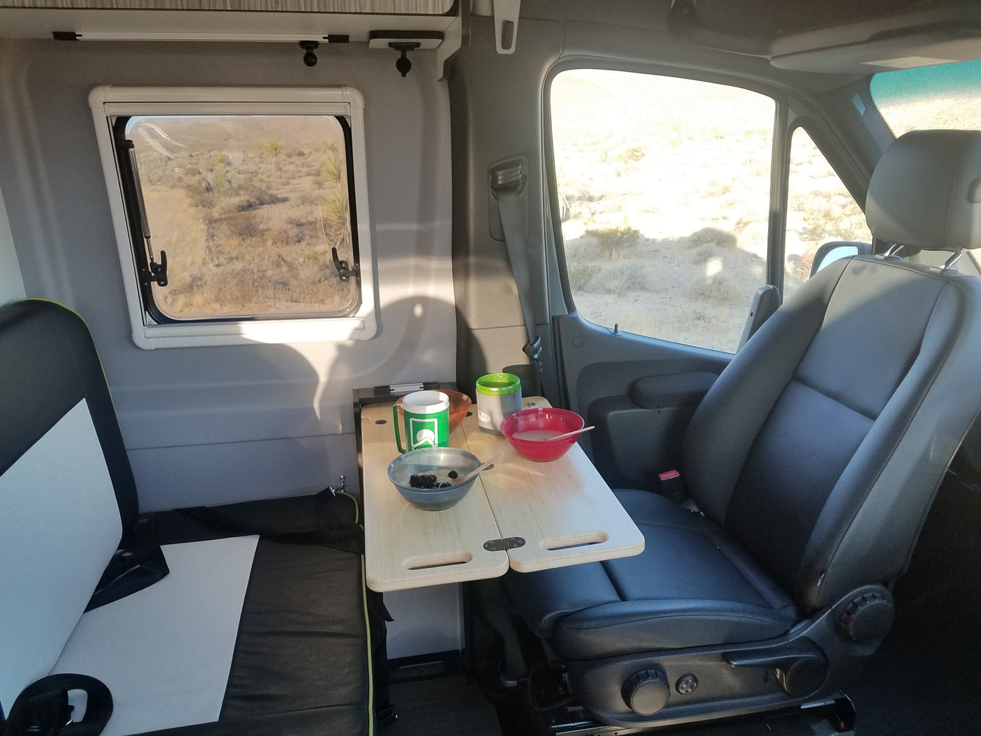 RV rental interior with breakfast on a portable table and a scenic desert view from the window.