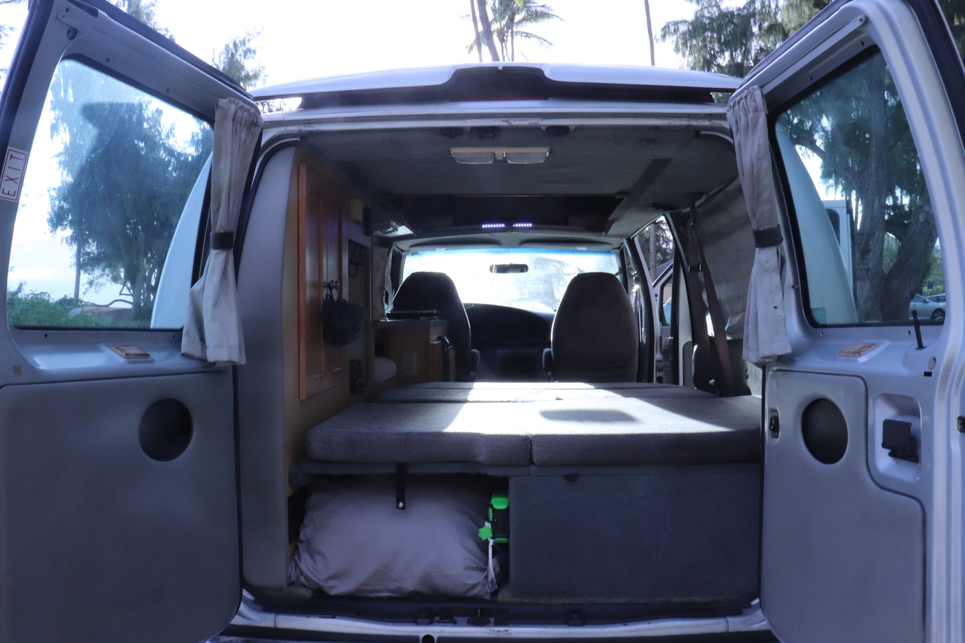 Inside an RV rental: cozy camper van interior with bed, storage, & front seats, ready for a road trip.