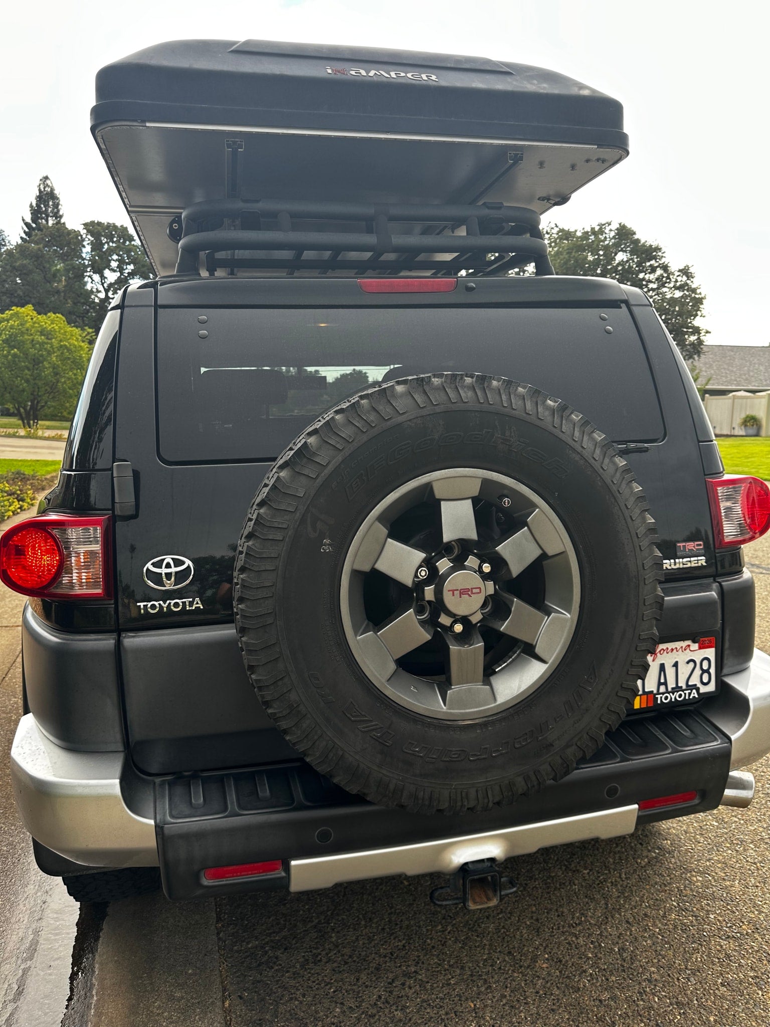 Rear view of a black Toyota FJ Cruiser SUV with an iKamper rooftop tent, perfect for an rv rental outdoor adventure. Features a spare tire and hitch.