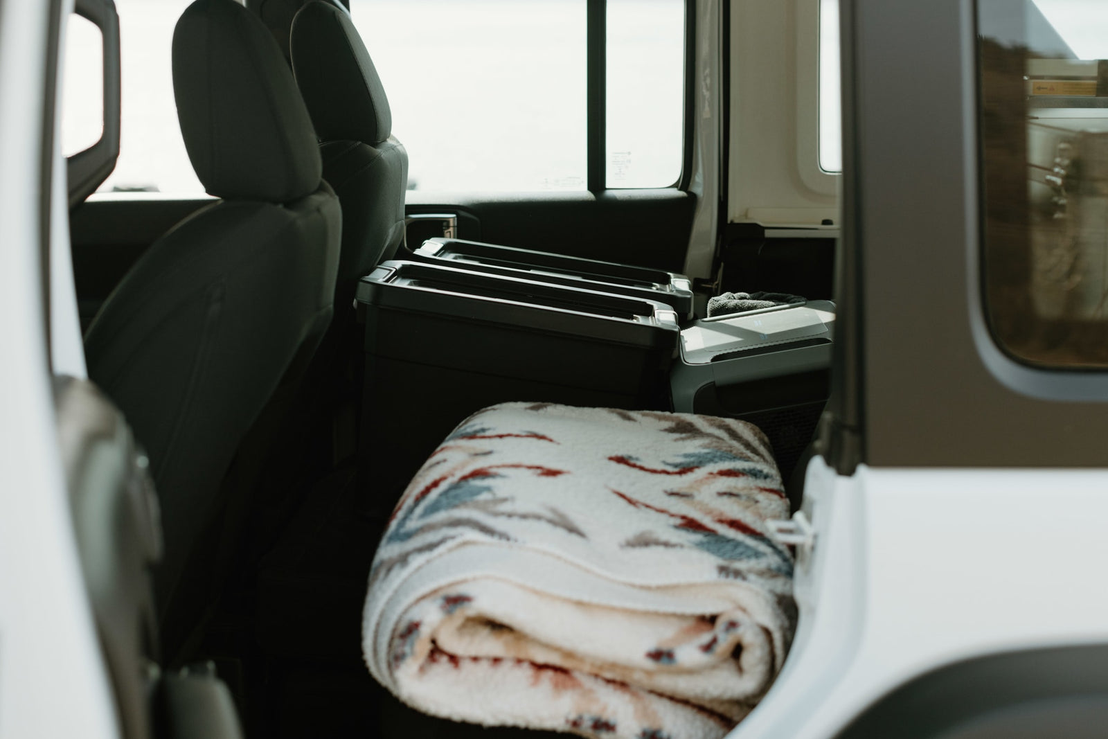 Interior of an RV rental: packed storage, cooler, & cozy blanket ready for adventure.