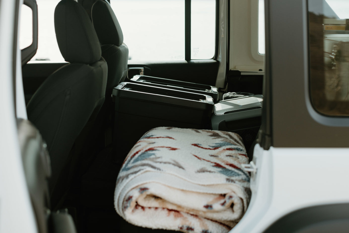 Interior of an RV rental: packed storage, cooler, & cozy blanket ready for adventure.