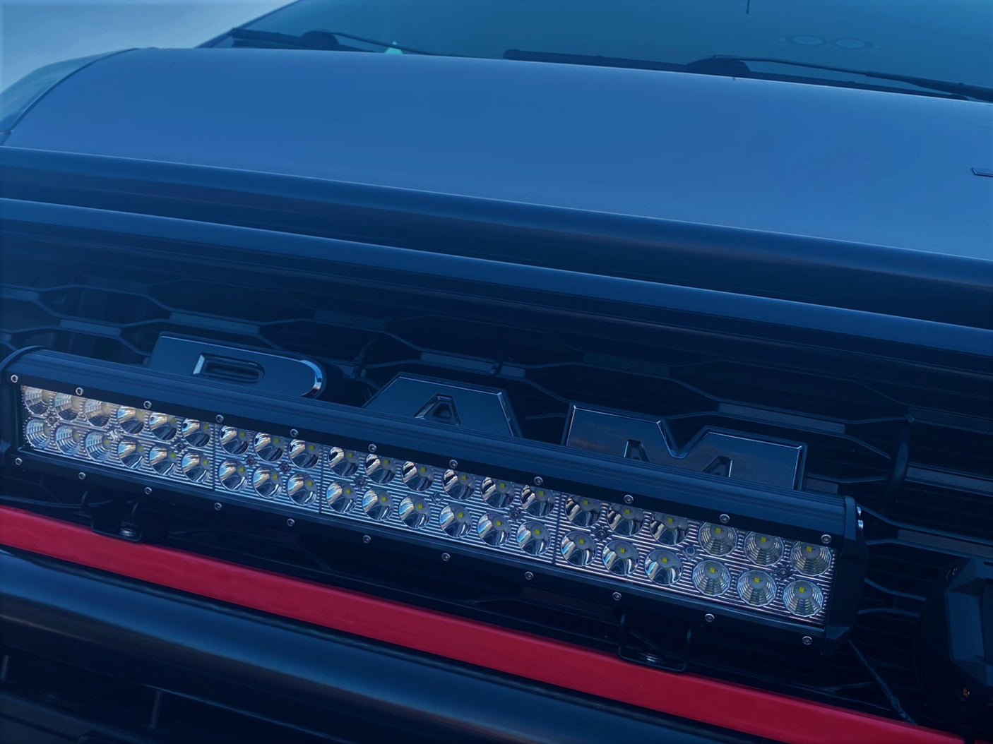 A rugged RAM truck, ideal for rv rental trips, showcases a prominent LED light bar mounted on its dark grille.