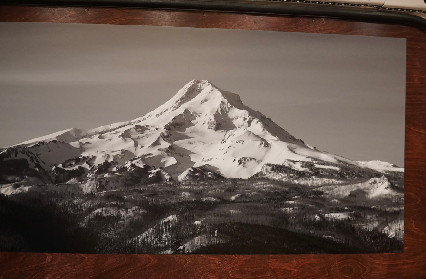 A serene black and white print showcases a snow-capped mountain above dark forests, inspiring RV rental trips.