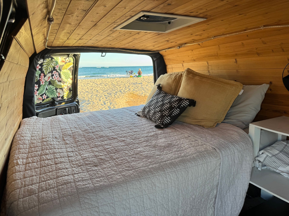 Cozy RV rental interior: a bed with wooden walls & floral curtains — photo 1