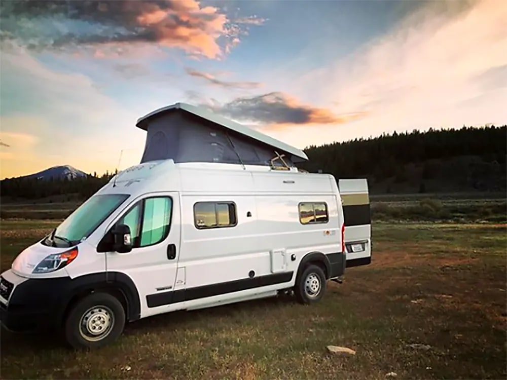 White pop-top RV rental in a scenic field