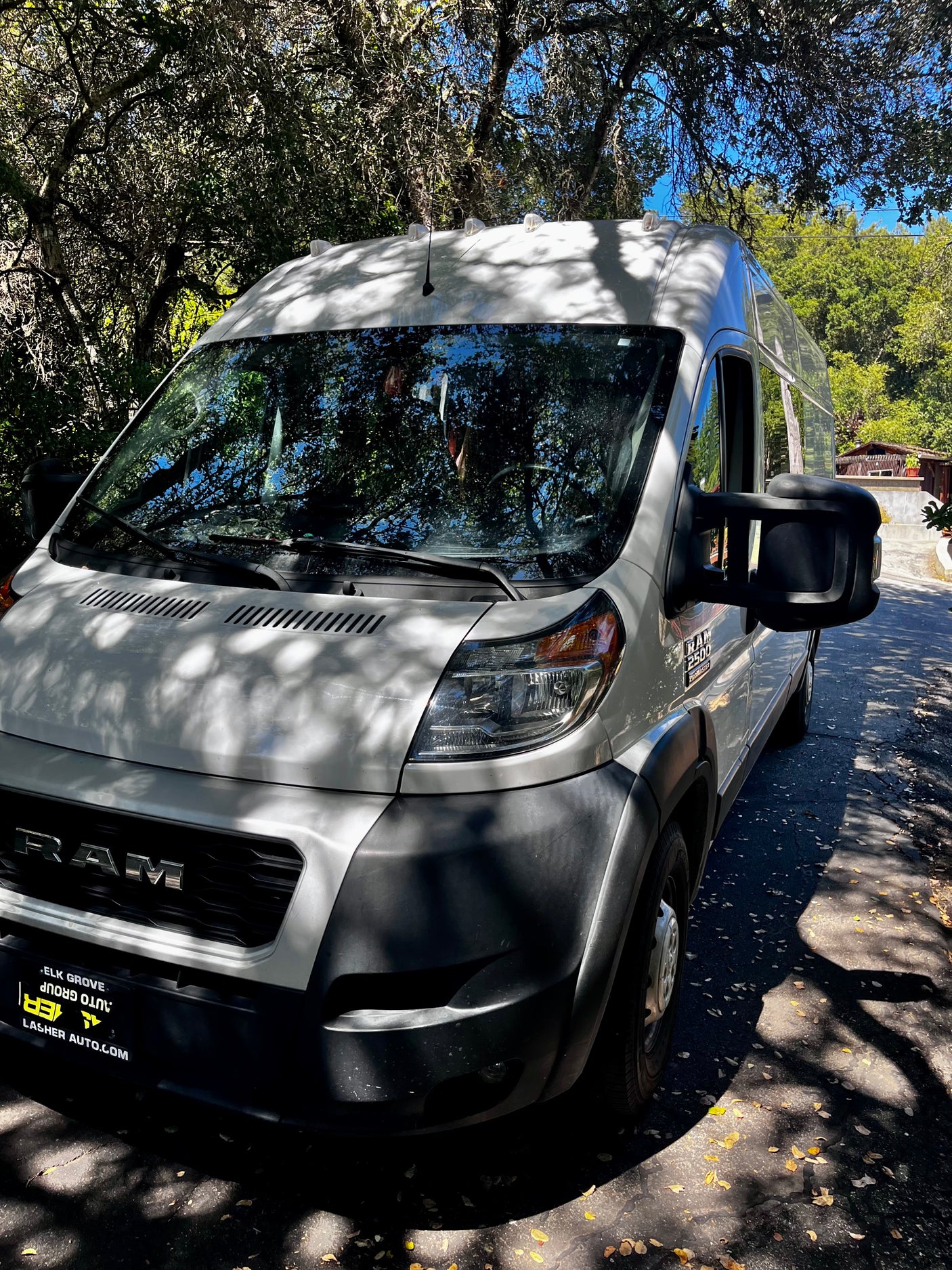 White Ram ProMaster van, ideal for your next rv rental adventure, parked on a sunny, tree-lined path.