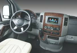 RV rental interior: A modern van's driver's area with dark steering wheel, wood trim, and large central display screen. — photo 11