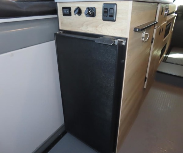 and slatted bed/storage area.|Compact 2-burner gas stove with stainless steel cooktop and open lid in an RV rental.|Modern RV rental interior: Solis camper van with compact kitchen