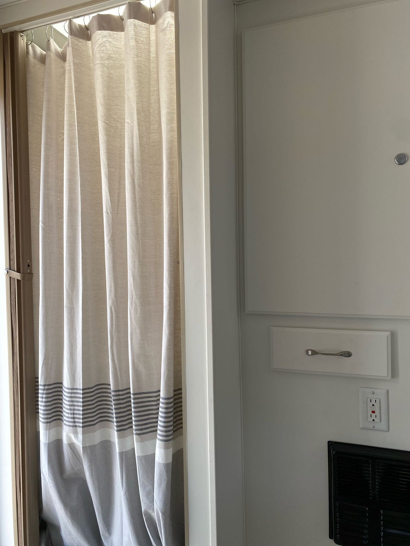 RV rental details: Striped curtain, built-in drawer, GFCI outlet, and vent showcase functional, compact design.