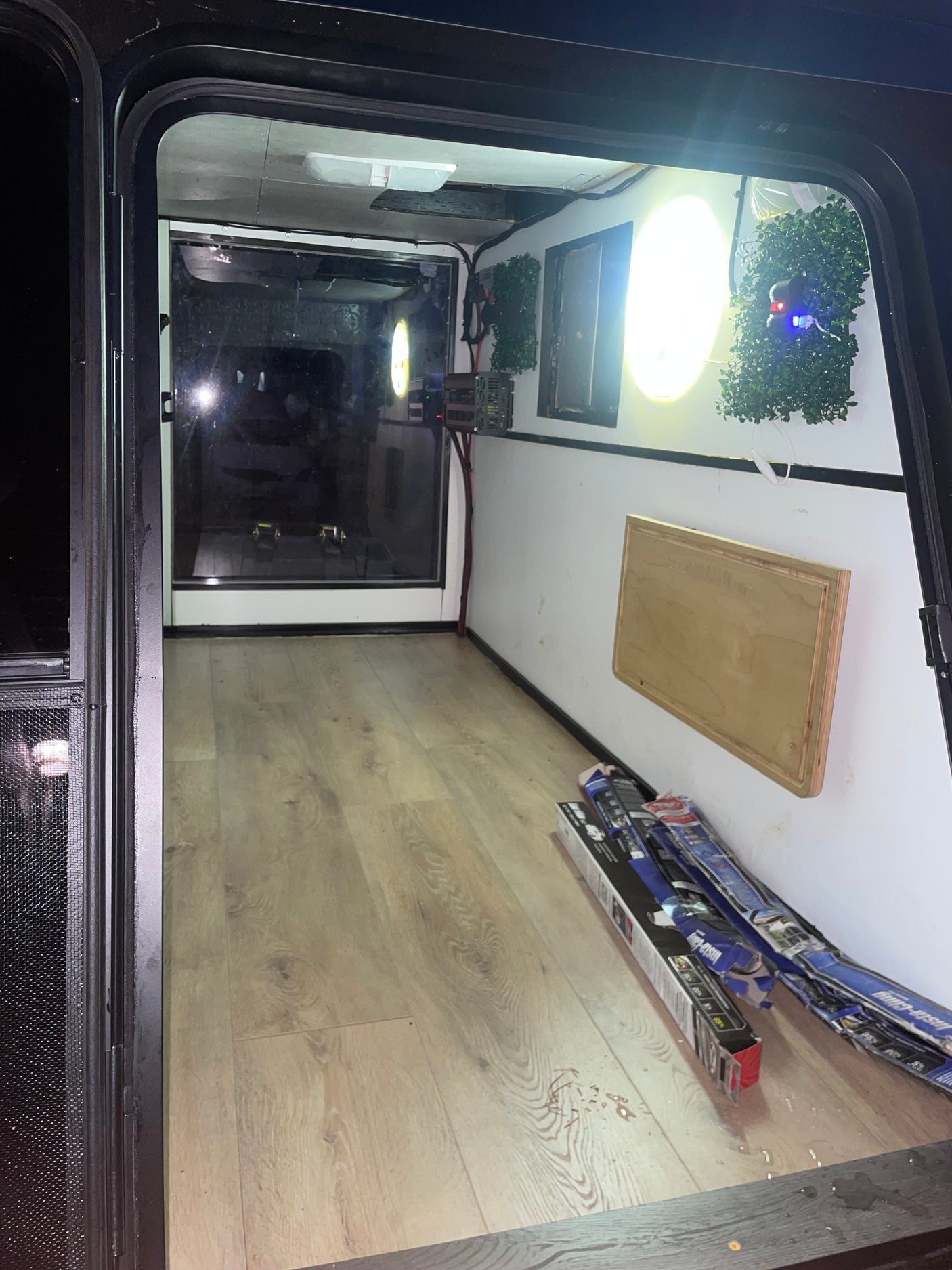 RV rental utility space: A compact interior with laminate flooring, bright lights, electronics, and a fold-down table.