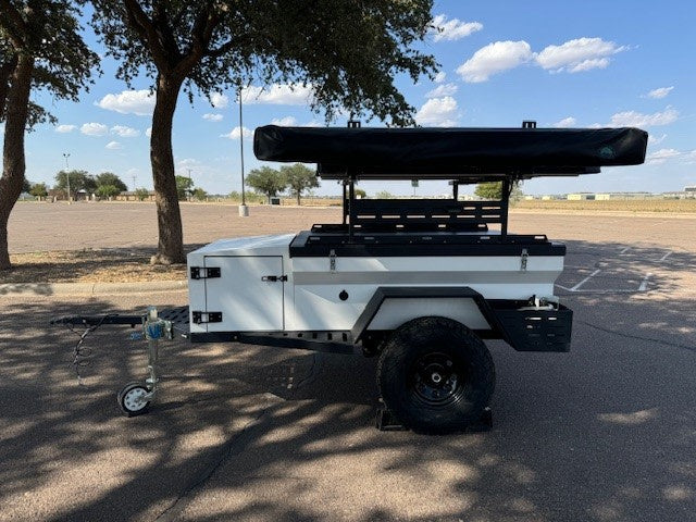 & trailer w/ tent at an overland camp. Experience this adventure with an RV rental!|Explore with this rv rental! A compact camping trailer features a deployed rooftop tent