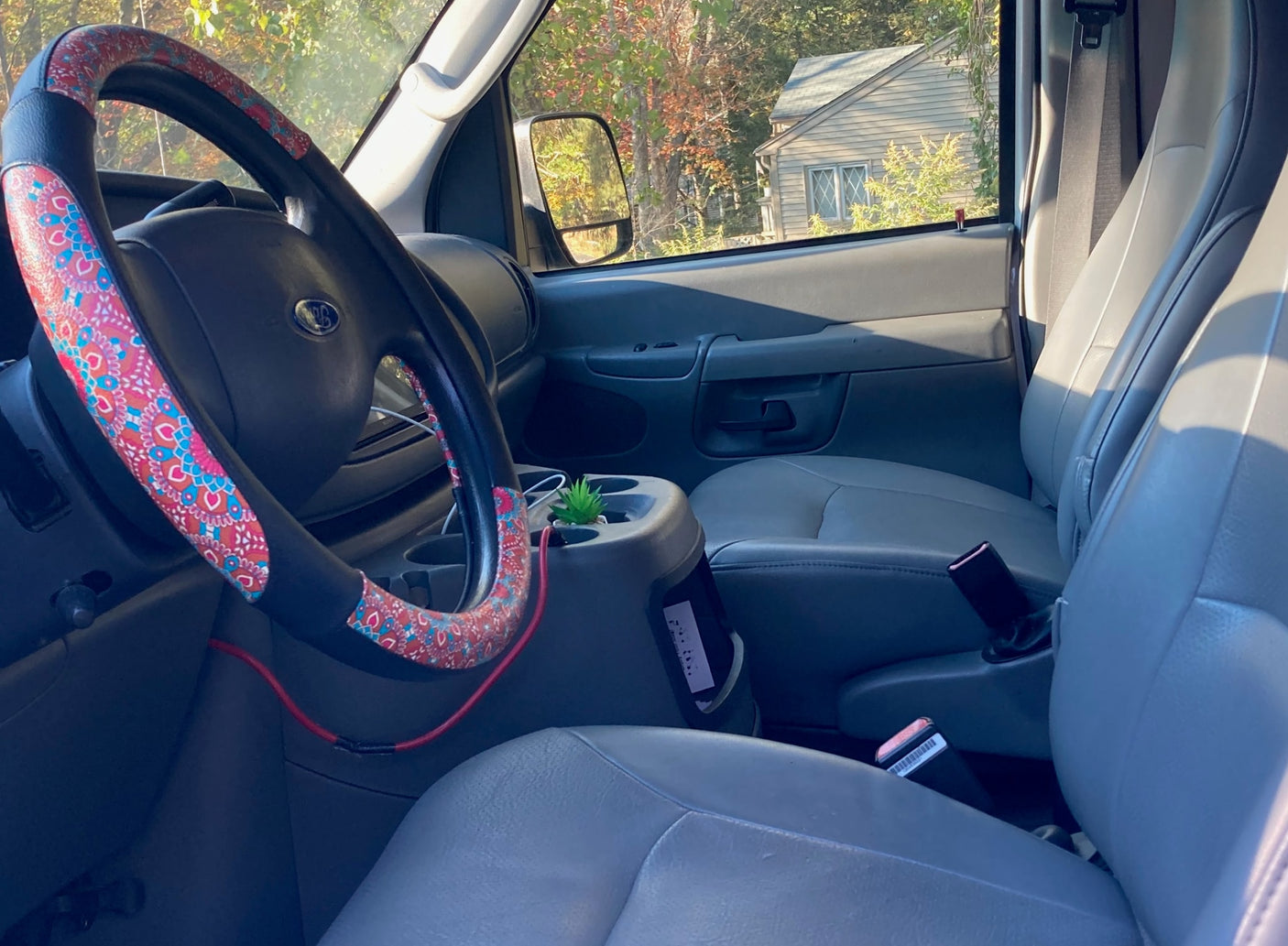 parked on a gravel path with autumn leaves.|White high-top van with 'Bel-Air' script