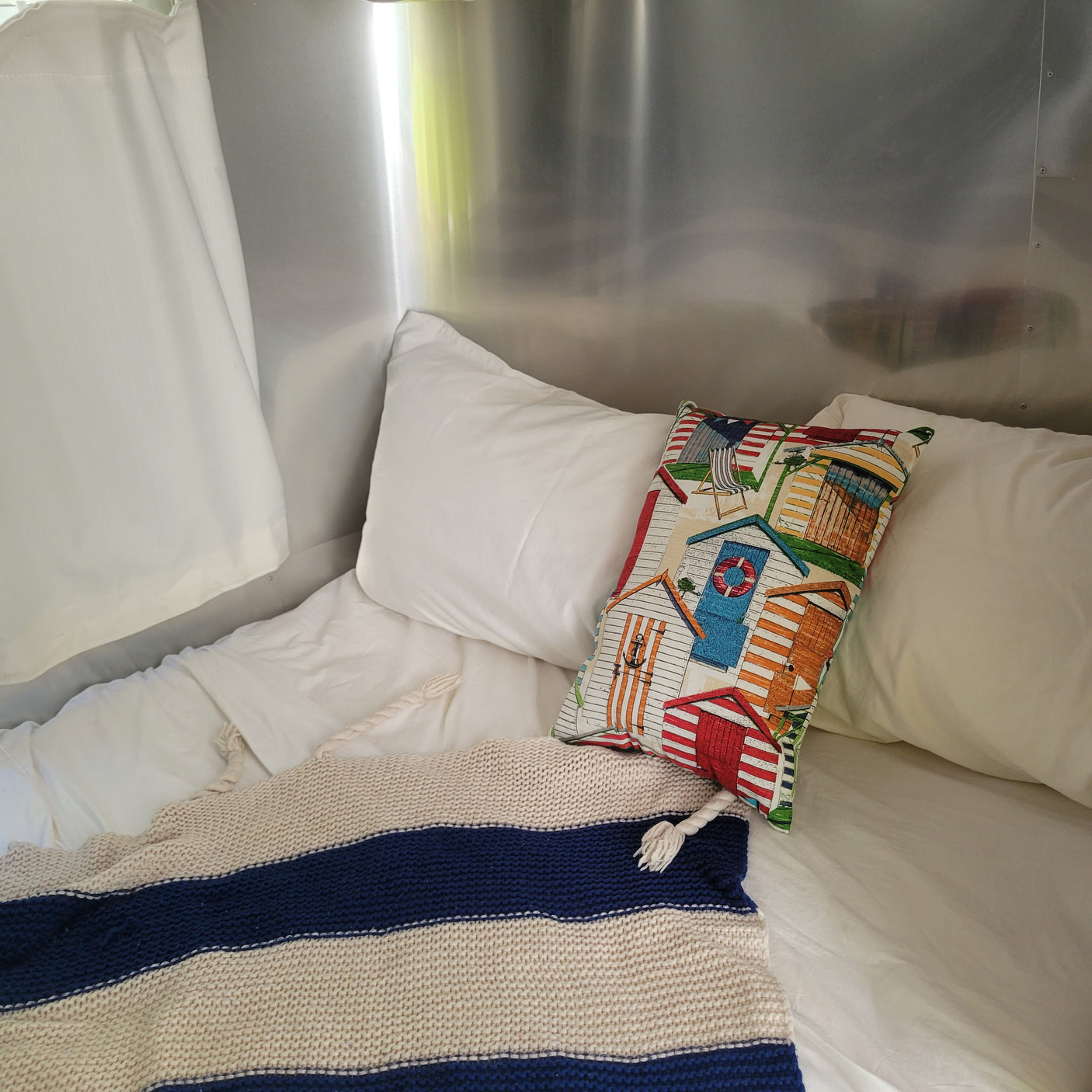 RV rental: Cozy bed with striped blanket, beach-themed pillow, and polished interior.