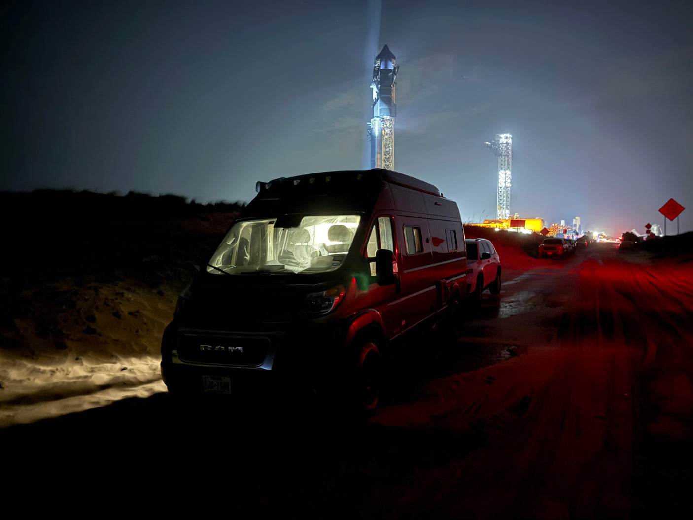 Night shot: An RV rental parked near the brightly lit SpaceX Starship launch tower at Boca Chica, Texas.