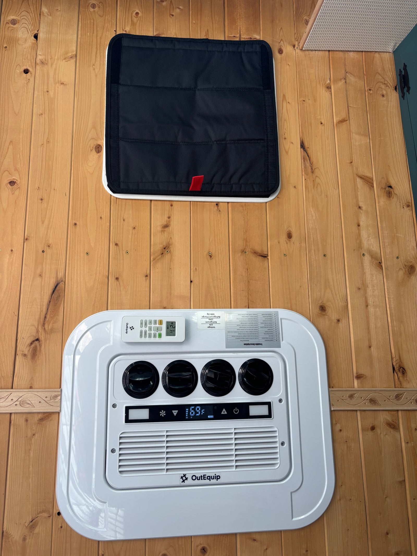 RV rental interior with OutEquip climate control (69°F), air vents, remote, and a black padded cover on wood paneling.