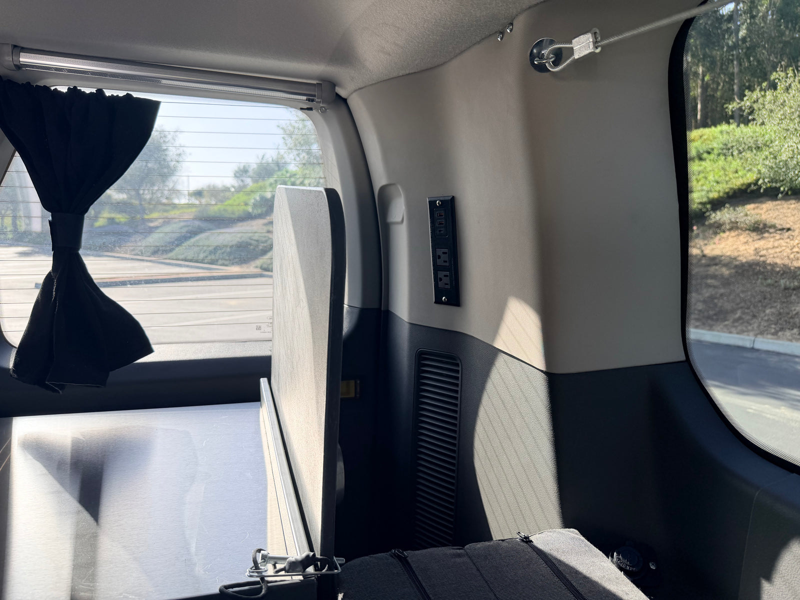 Inside a personalized rv rental: features a bed platform, essential power outlets, and a convenient privacy curtain.