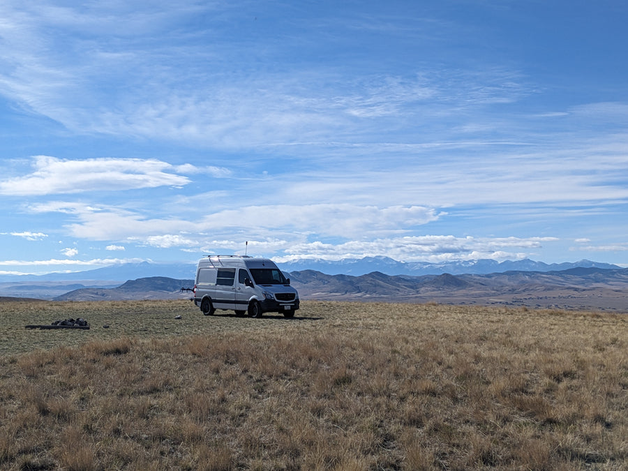Freedom on wheels! An RV rental Sprinter van in a golden field, with snow-capped mountains under a blue sky.