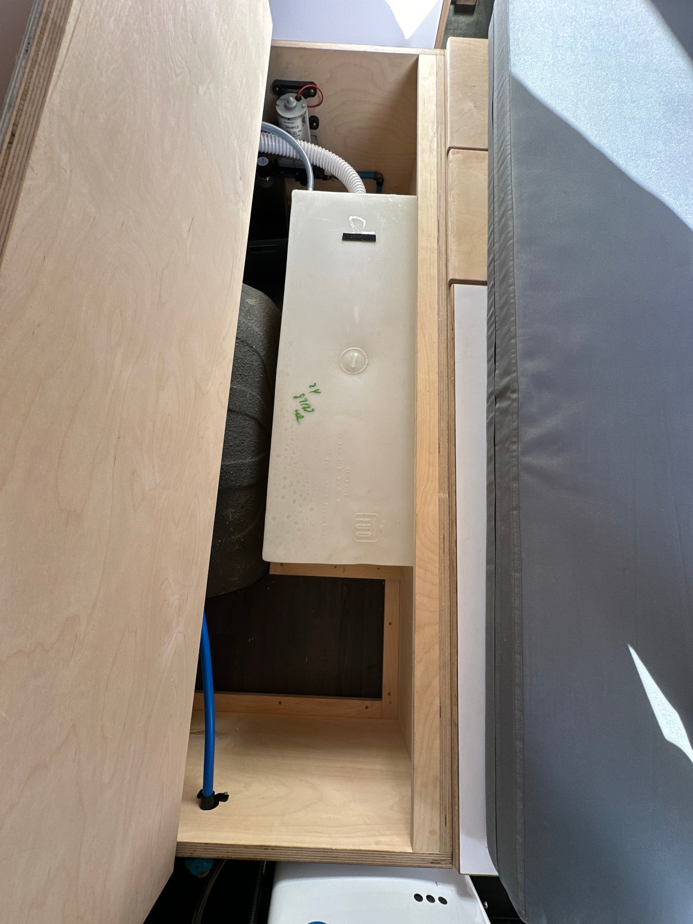 RV rental water system: inside a camper van, showing a white water tank, SHURFLO pump, and plumbing.