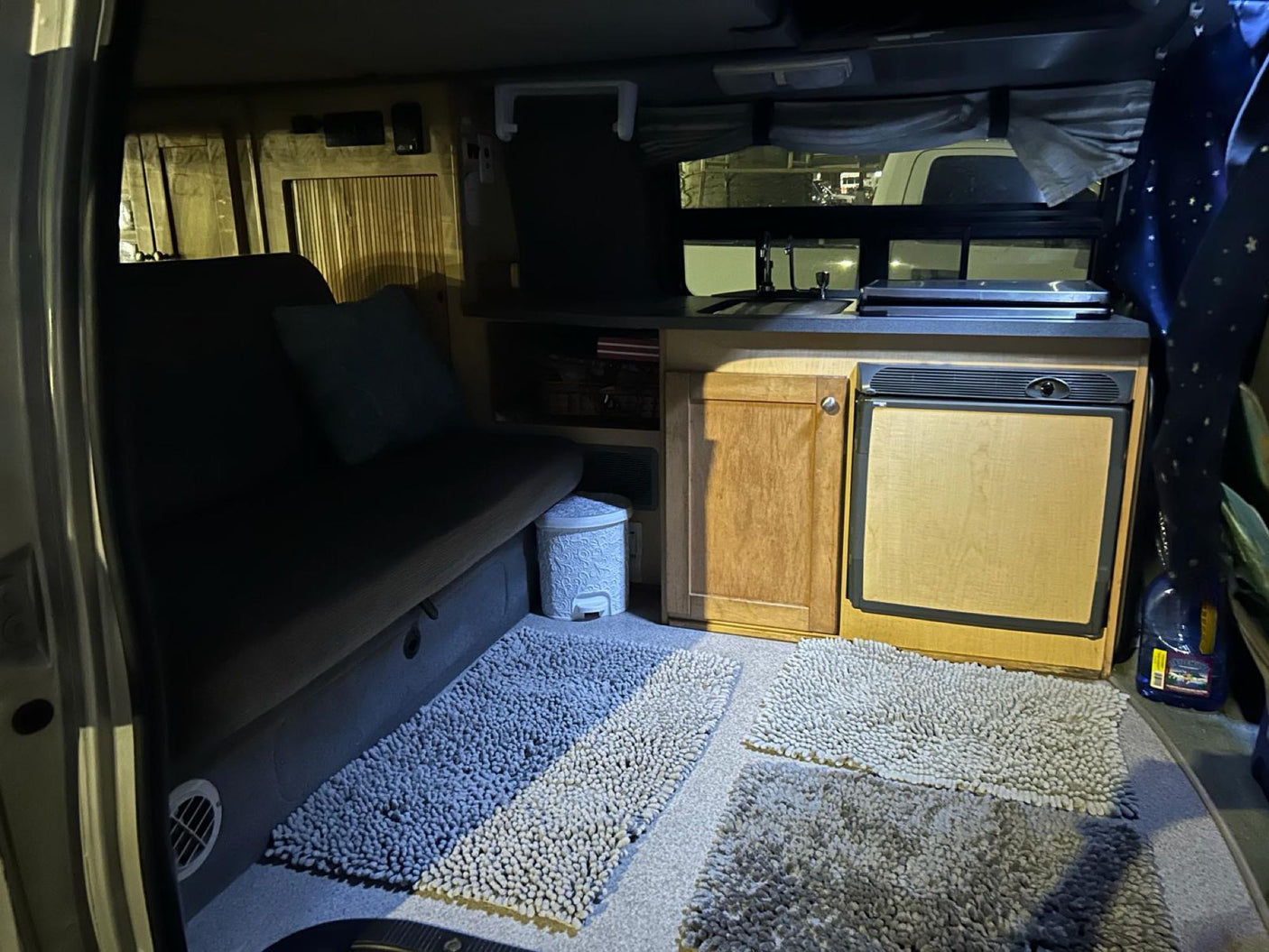 Step inside this cozy RV rental's living space: a compact kitchen, comfy bed, and soft floor mats for ultimate comfort.