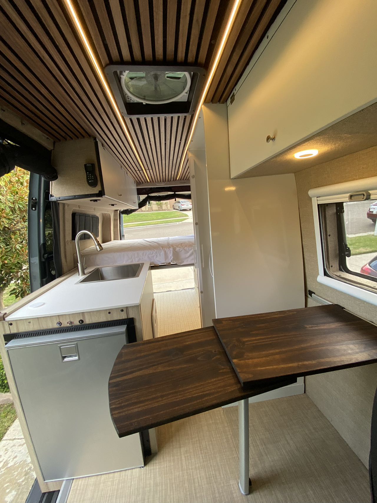 perfect for rv rental adventures. Features swiveling seats & wooden table for versatile living.|RV rental interior featuring a stylish kitchenette — photo 8