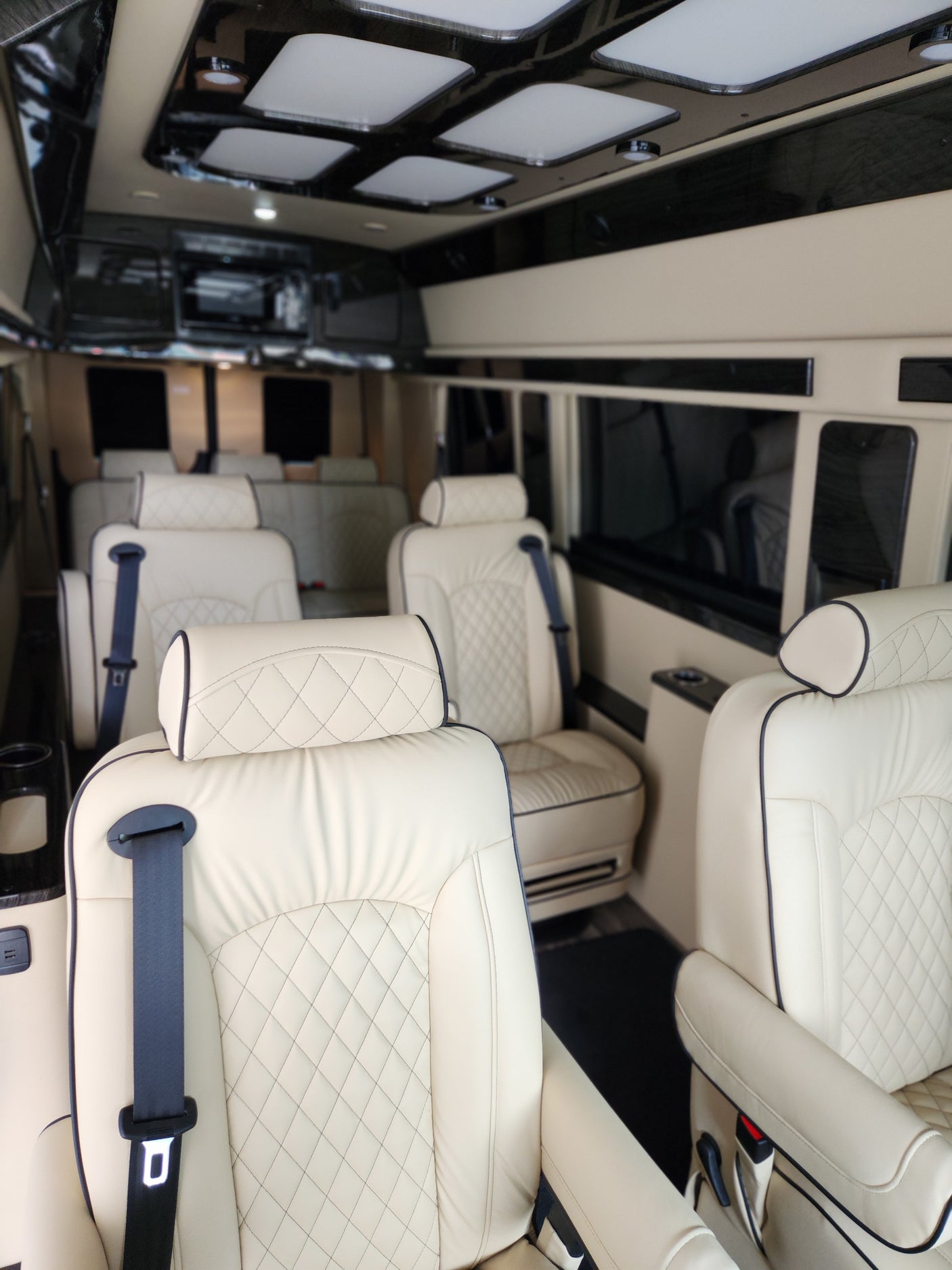 Experience comfort in this luxury RV rental van interior with quilted leather seats and modern lighting, perfect for travel.