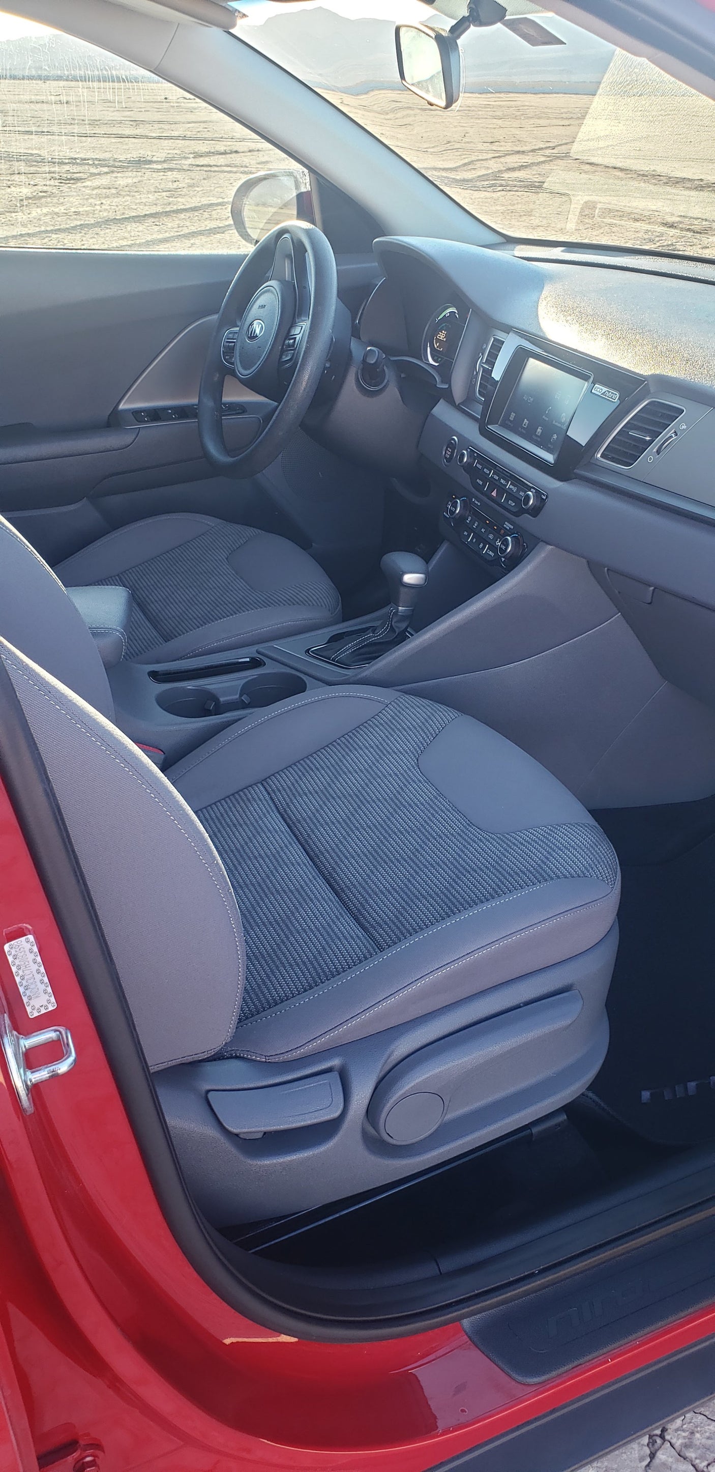 View of a modern hybrid car interior (likely Kia Niro), ideal for your RV rental trip. Comfy seats & clean dashboard.