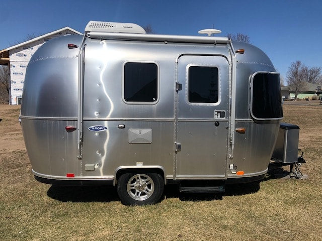 This sleek silver Airstream Sport travel trailer, great for an RV rental, is parked on grass, ready for your next adventure.