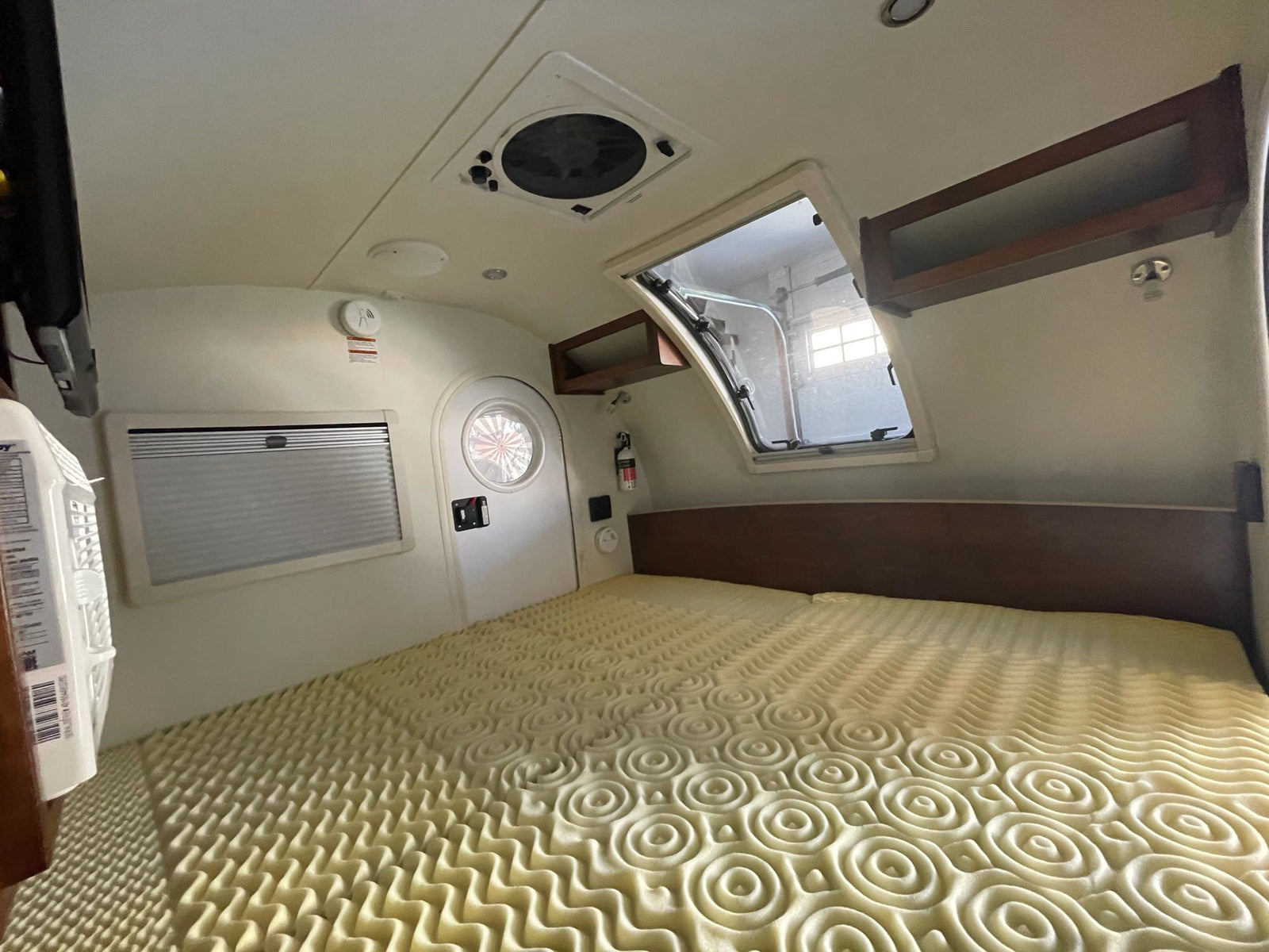 parked in a garage.|Spacious RV rental bedroom showcasing a bed with foam topper