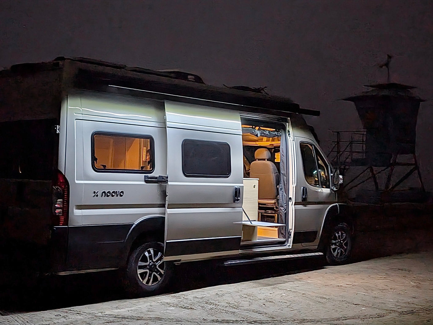 Modern X noovo camper van at night, side door open and interior lit. Great rv rental for compact adventures. — photo 7