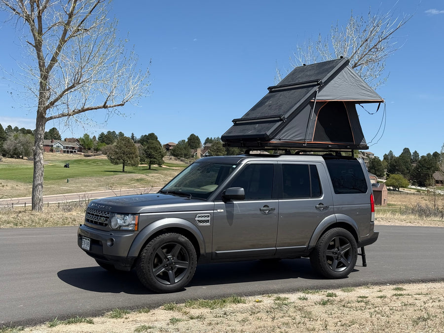 Gray Land Rover SUV with deployed rooftop tent, ready for a rugged RV rental outdoor adventure.
