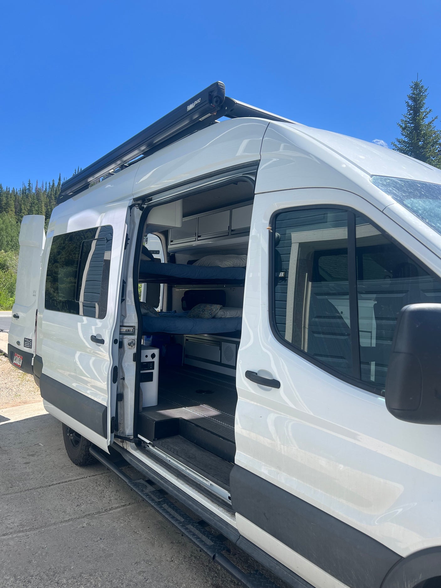 White camper van rv rental with open door revealing bunk beds and interior. Ideal for your next adventure.