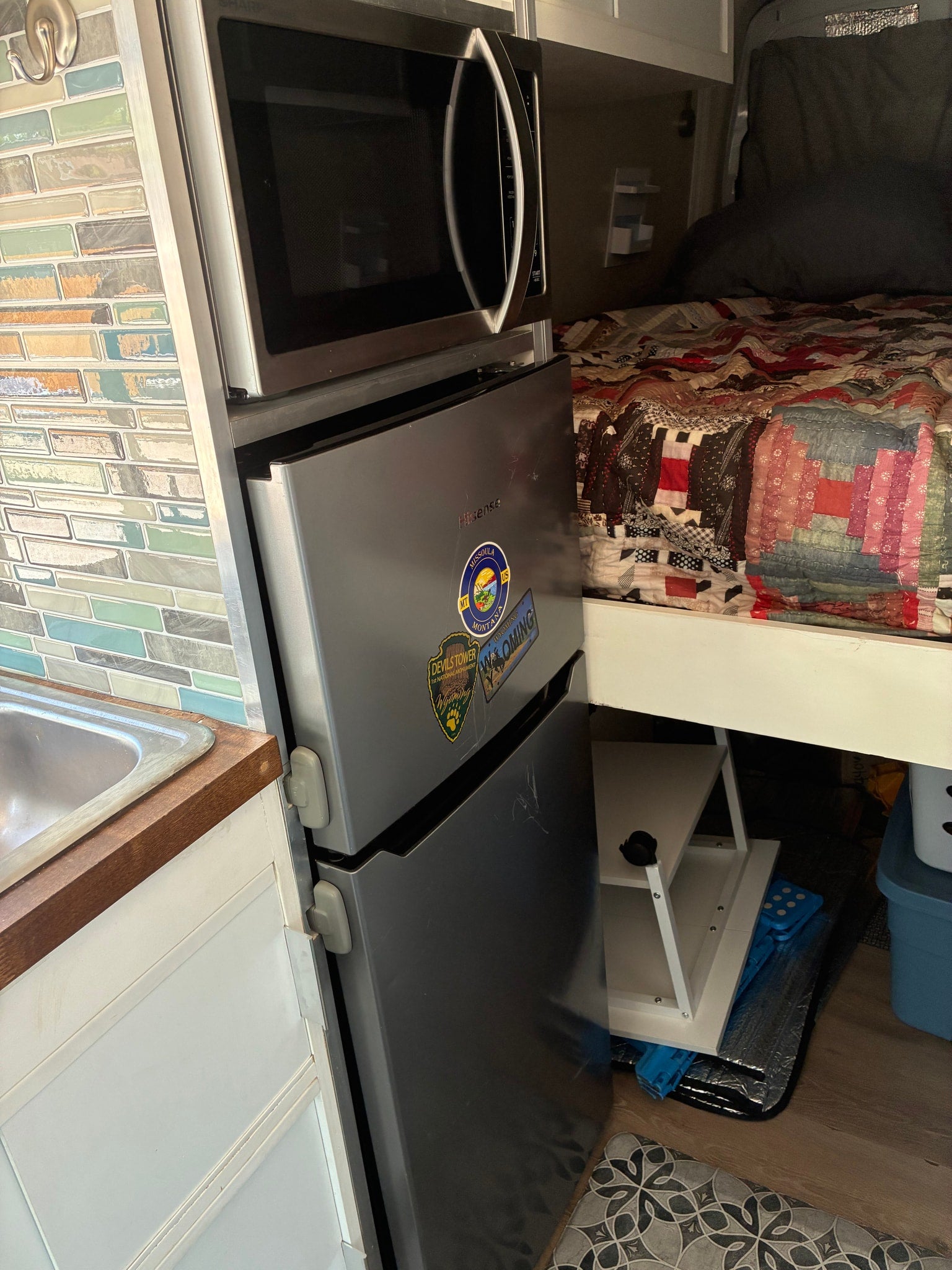 Functional rv rental kitchen with microwave over a Hisense mini-fridge (with travel stickers) next to a sink.