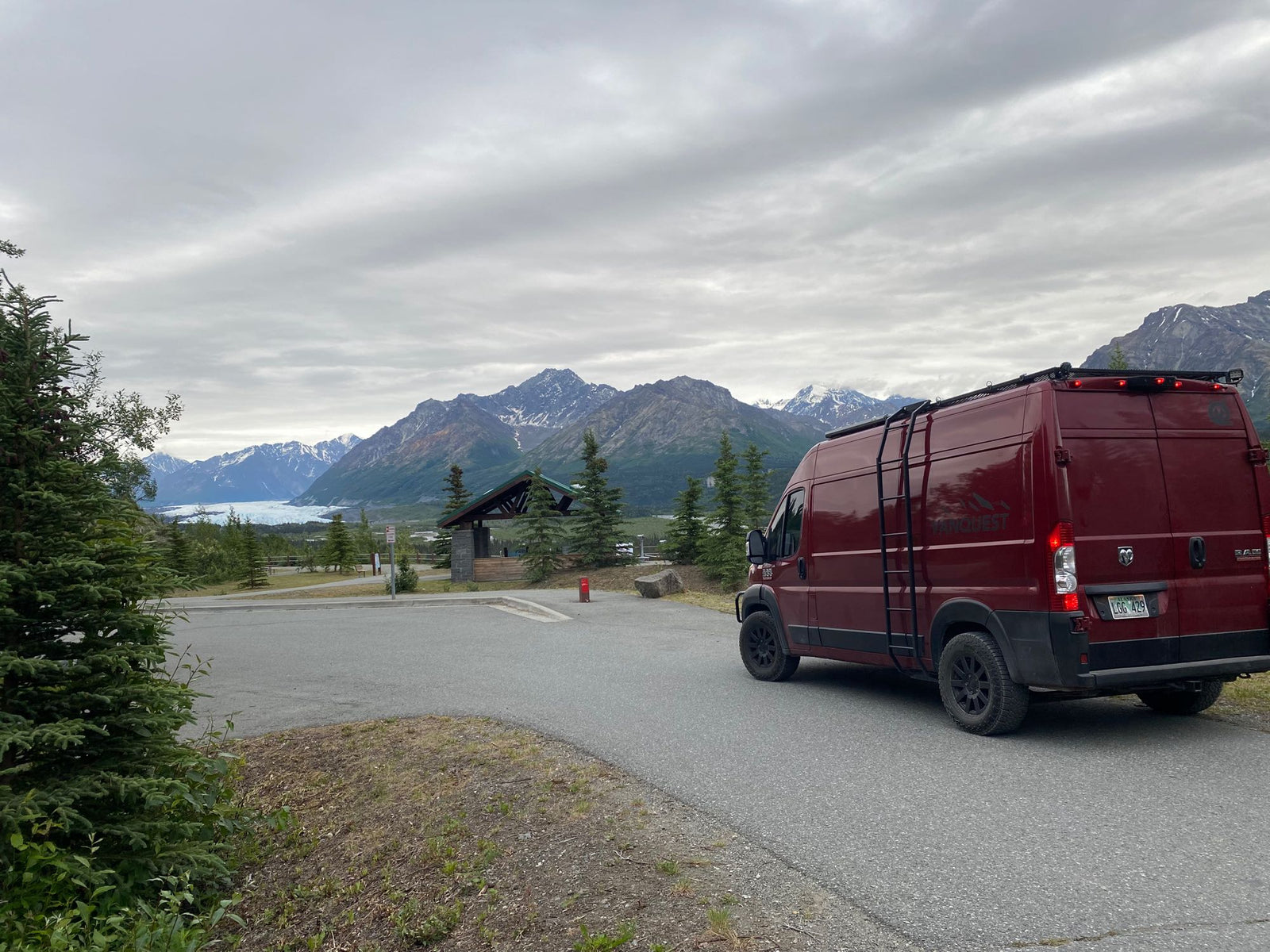 perfect for an RV rental compact kitchen setup.|Cast iron skillet on a Eureka! SPRK portable camp stove inside an RV rental. Ideal for cooking during van life.|Red RV rental campervan leveled for camping with yellow blocks. Shows rugged tire & ladder.|This red camper van