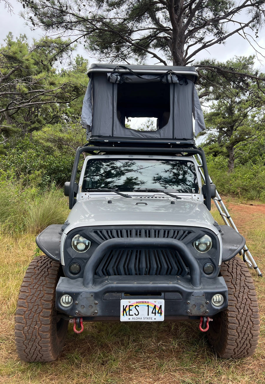 Grey Jeep Wrangler with rooftop tent, ideal for a unique RV rental camping adventure in Hawaii.