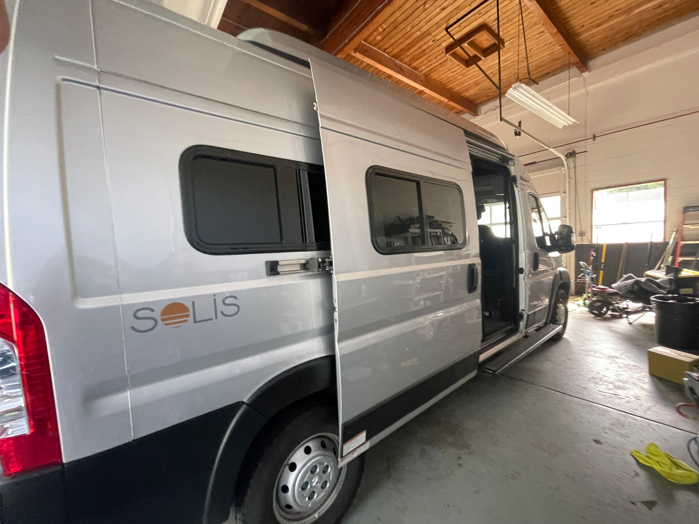 Winnebago Solis RV rental with side door open inside a garage, offering a glimpse of the versatile camper van interior.