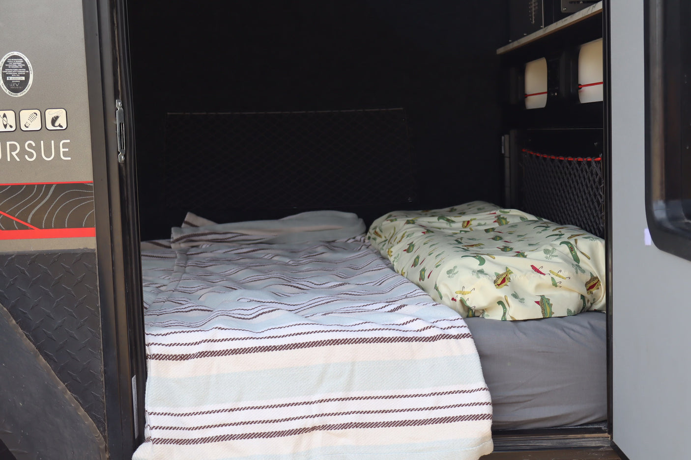 Cozy RV rental sleeping area with two beds and adventure gear storage. Perfect for travel trailer trips.