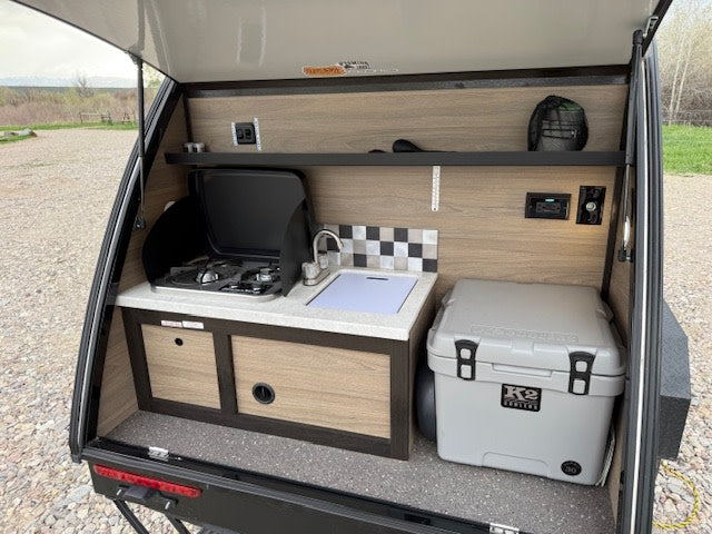 its open door shows a cozy interior.|RV rental camper interior: a compact bedroom with controls