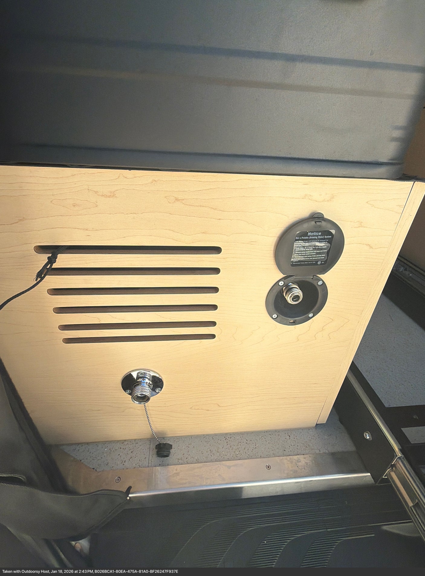 Utility panel inside an rv rental, showing a "Not Potable" water hookup, ventilation slats, and a drain plug.
